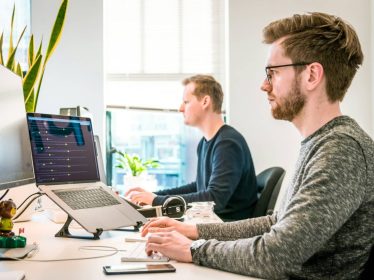 Two people working on computers in a shared office